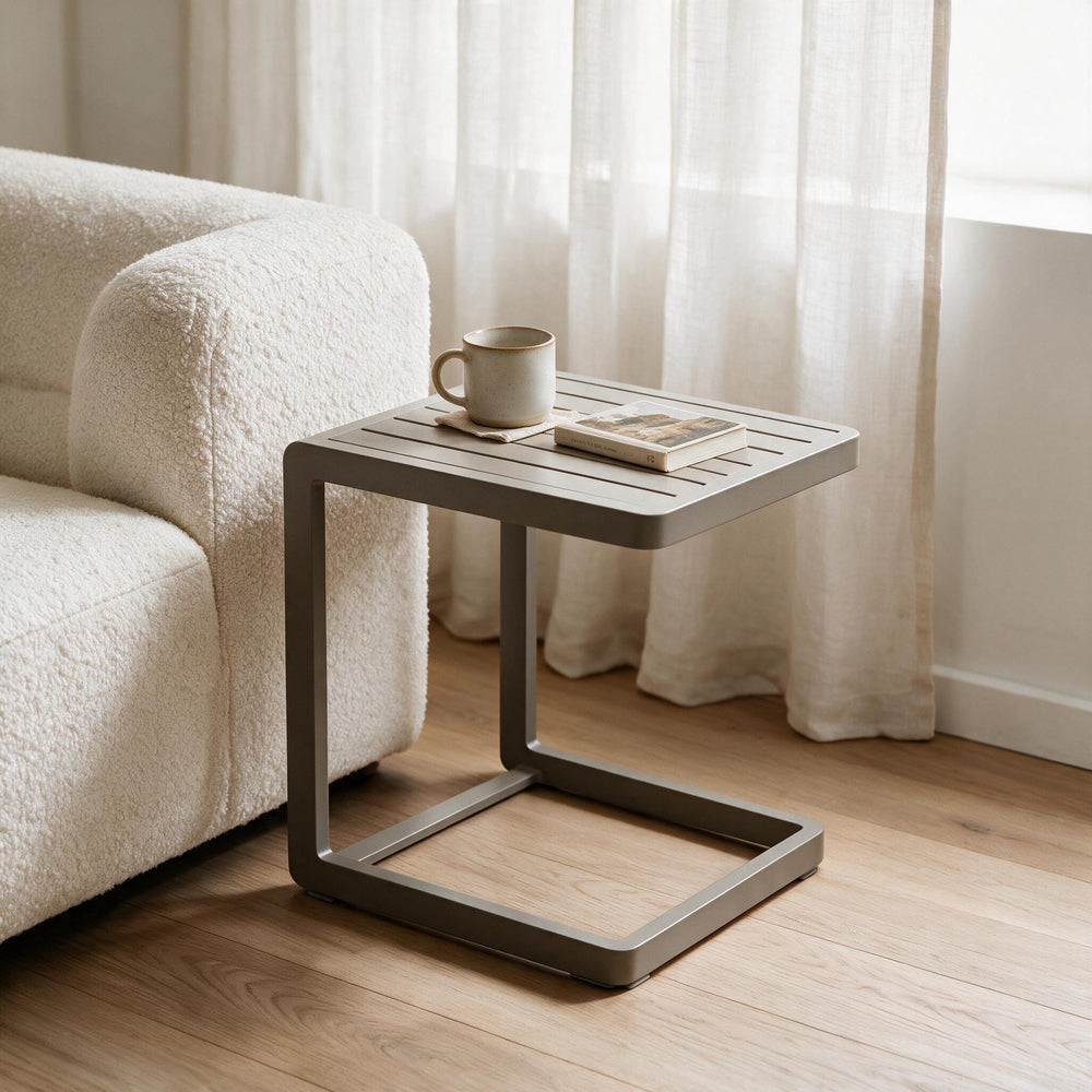 Ambientazione: tavolino Bizzotto Konnor 40×40 Rastin accanto a un divano in bouclé, con una tazza e un libro sul piano a doghe