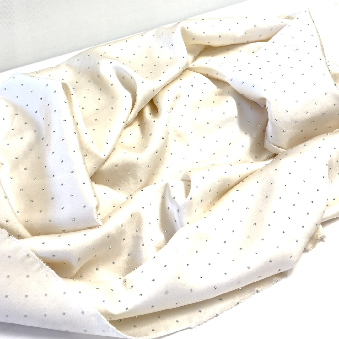 Tessuto bianco panna con brillantini argento drappeggiato in pieghe morbide