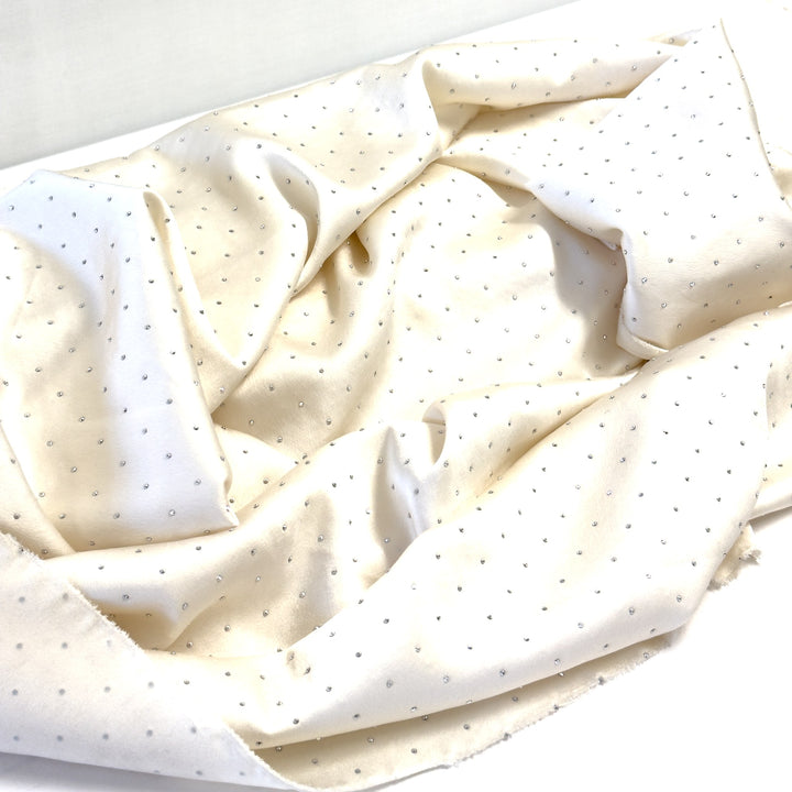 Cream fabric with silver rhinestones, draped in soft folds