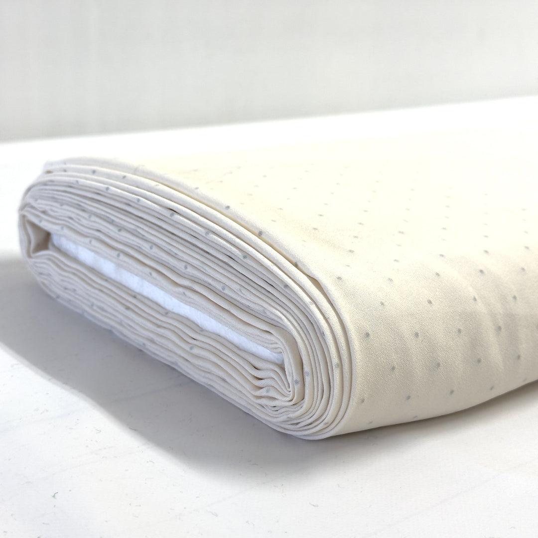 Roll of cream rhinestone fabric on a white background