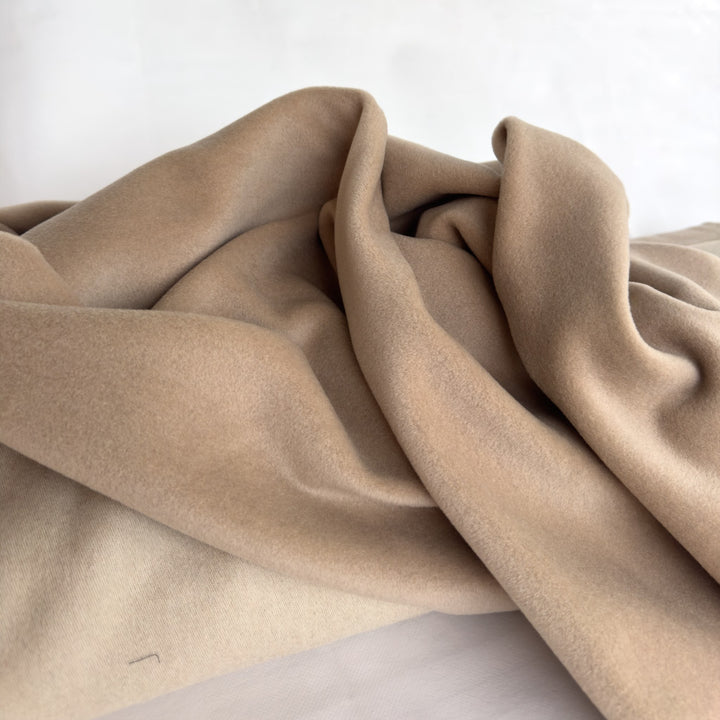 Draped coating fabric in sand, showing the soft folds of the wool and cashmere cloth