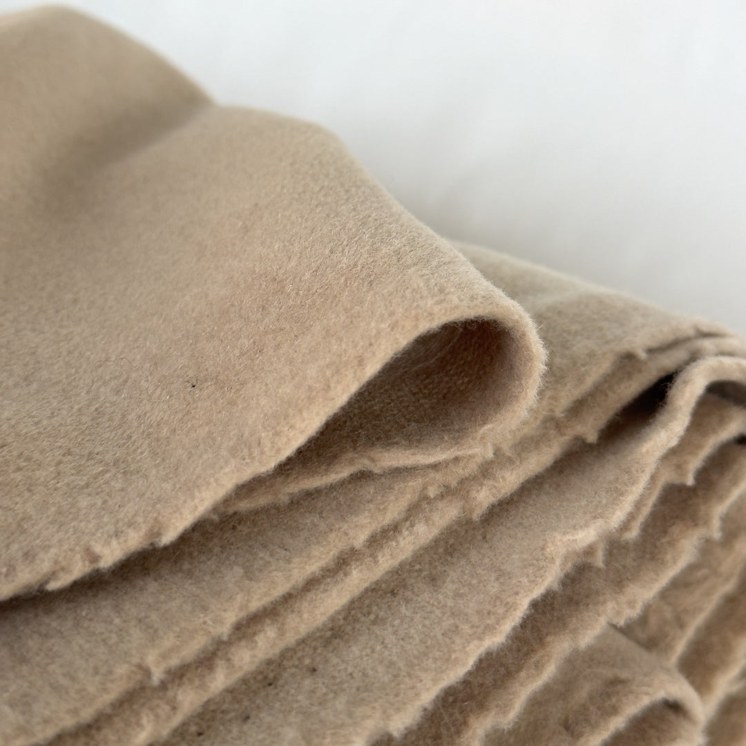 Close-up of the folded fabric in sand, showing the brushed surface and the thickness of the cloth
