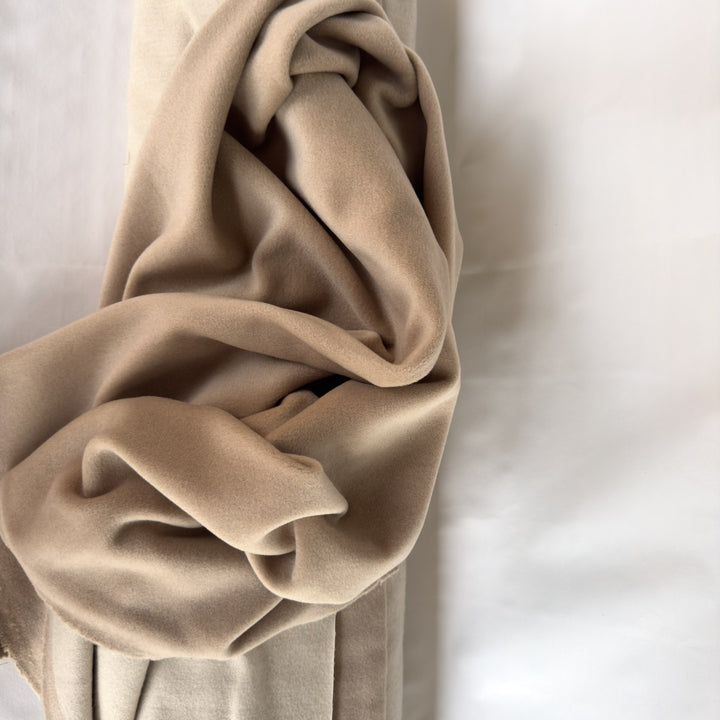 Coating fabric in sand, rolled up, on a white background