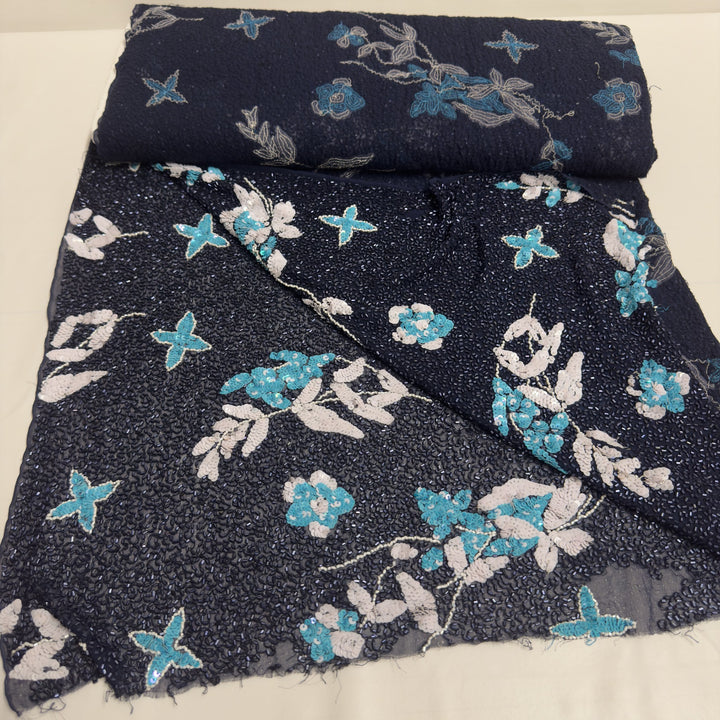 Dark blue chiffon fabric embroidered with flowers and beads, unrolled in the shop