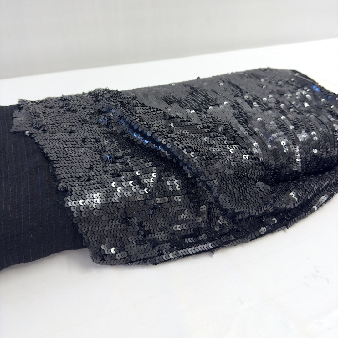 Tessuto con paillettes nere sul rotolo: a sinistra il rovescio in chiffon con le cuciture verticali