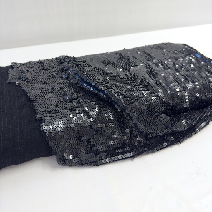 Tessuto con paillettes nere sul rotolo: a sinistra il rovescio in chiffon con le cuciture verticali