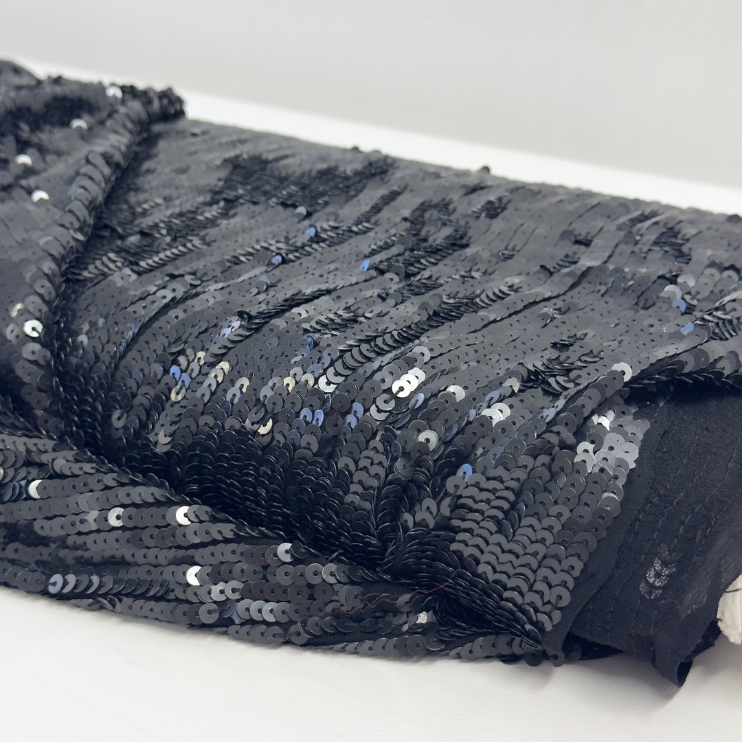 Paillettes nere da vicino, sovrapposte in file verticali sul chiffon nero