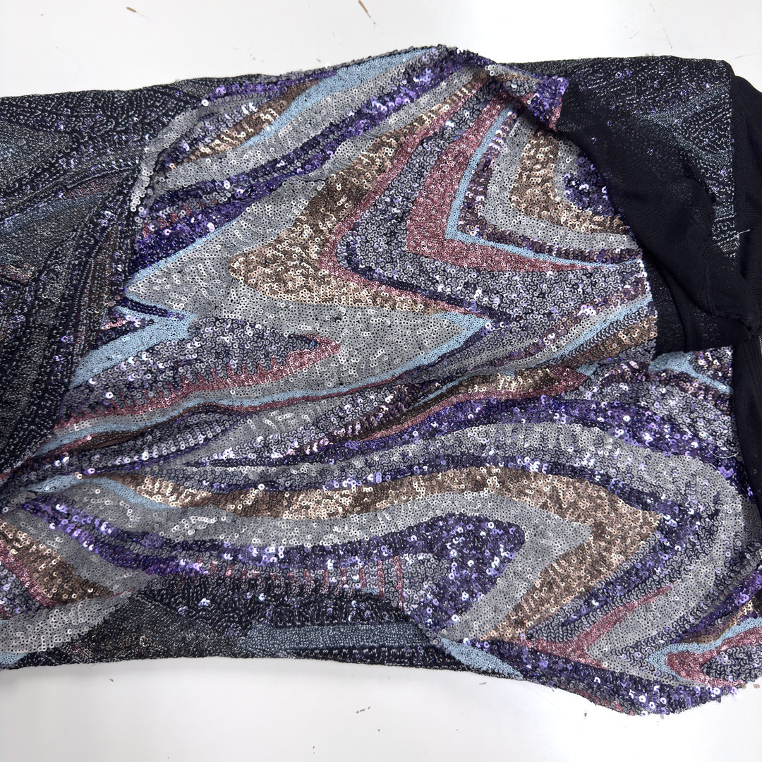 Tissu à petites paillettes en vagues violettes, roses, bronze et bleu ciel sur une base de tulle noir, posé à plat sur fond blanc