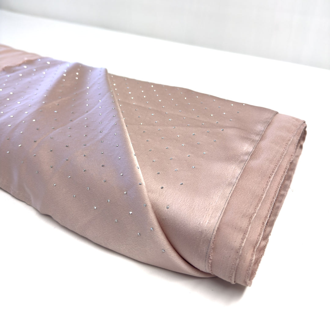 Bolt of pink silk with rhinestones, one end opened out, on a white background