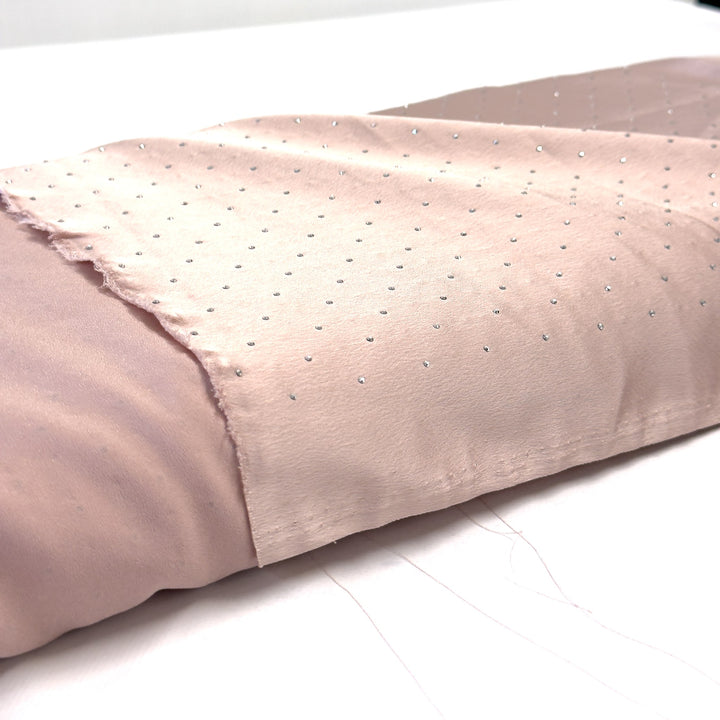 Pink silk fabric with rhinestones, laid out over the bolt