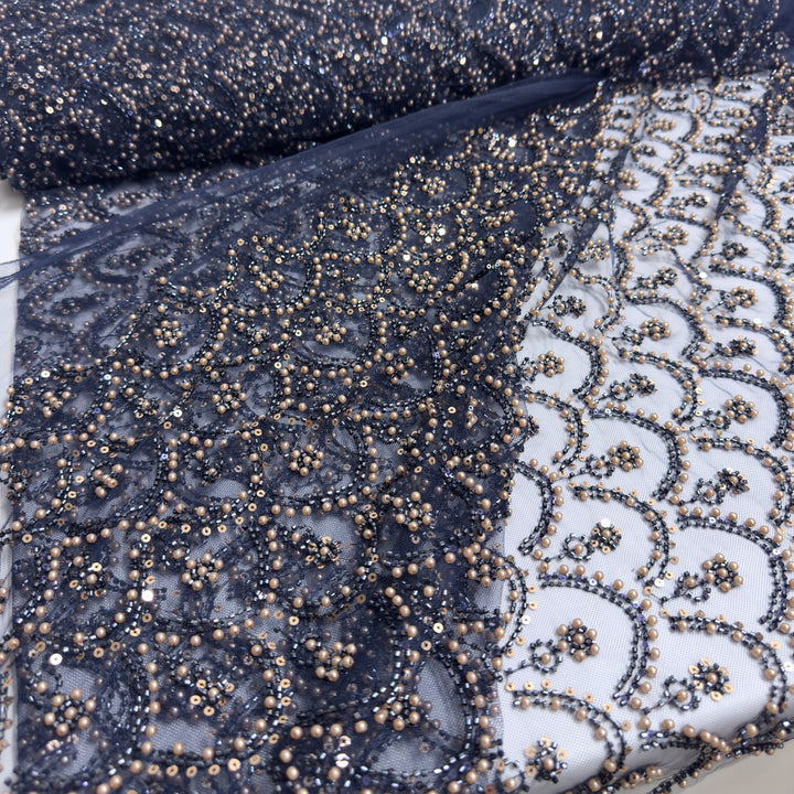 Tulle bleu foncé brodé de perles et de paillettes, en rouleau et déroulé sur fond blanc