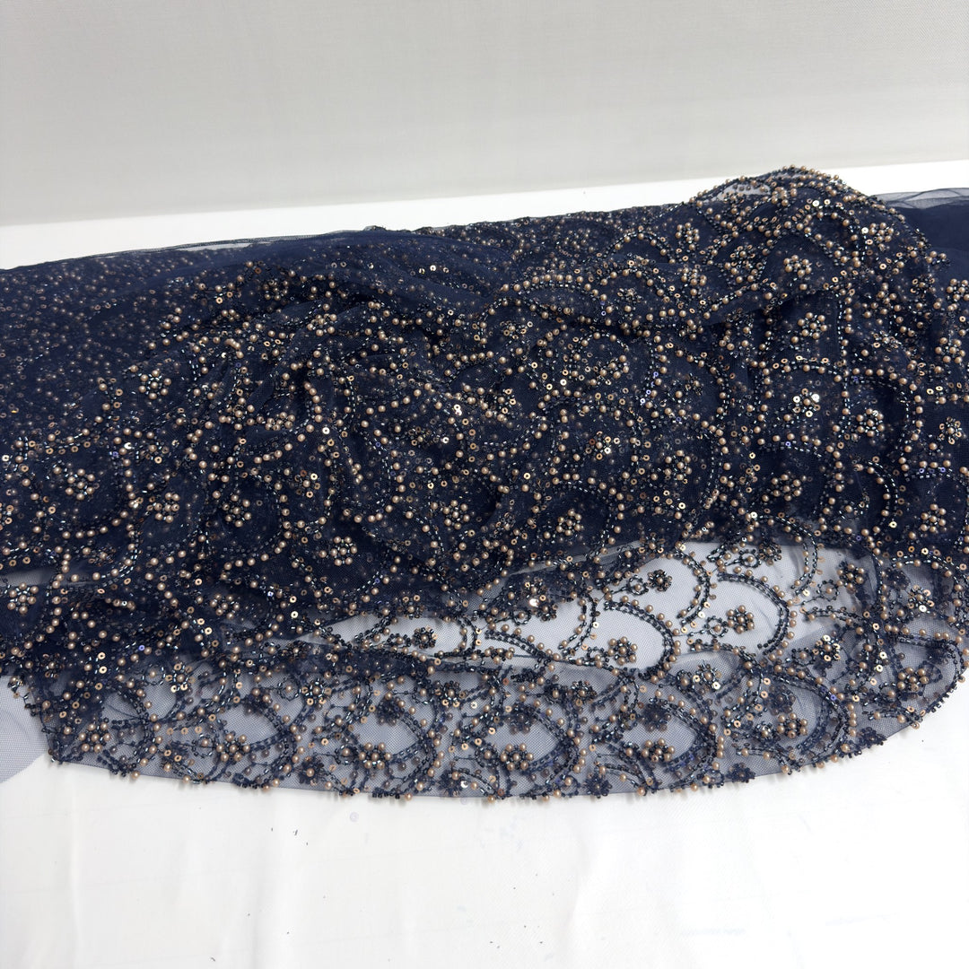 Tulle bleu foncé brodé de perles et de paillettes, drapé sur fond blanc