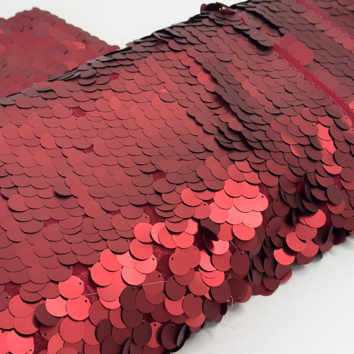 Tulle fabric with large red sequins, overlapping like scales, on a white background
