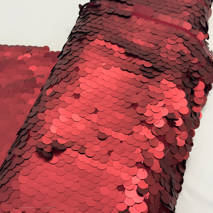 Roll of fabric with large red sequins, seen close up